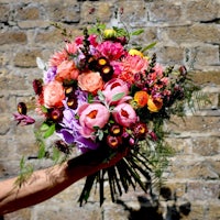a person holding a bouquet of flowers in front of a brick wall