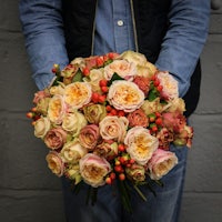 a man holding a bouquet of roses and berries