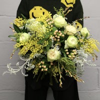 a woman holding a bouquet of yellow and white flowers